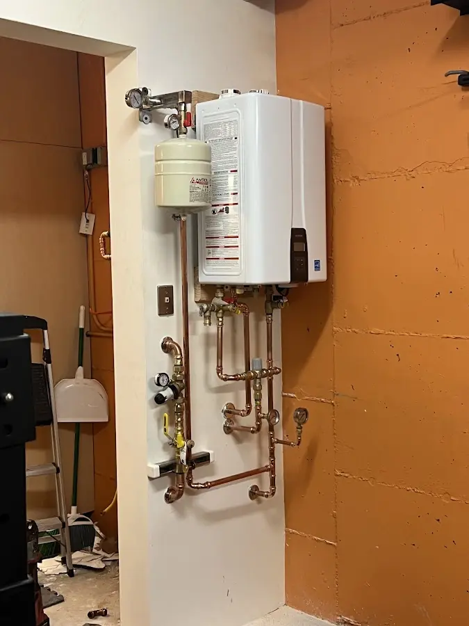 Plumbing technician inspecting water heater connections in Lysander